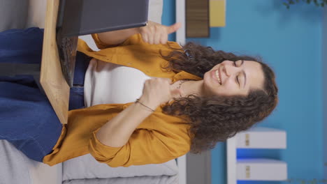 Vertical-video-of-Young-woman-looking-at-laptop-making-positive-gesture.
